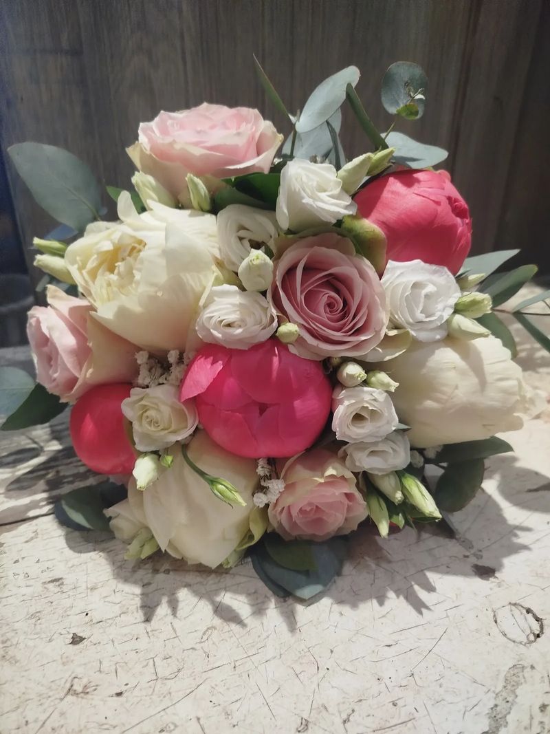 Bouquet de mariée rond composé de pivoines fuchsia, de roses pâles et de lisianthus blancs