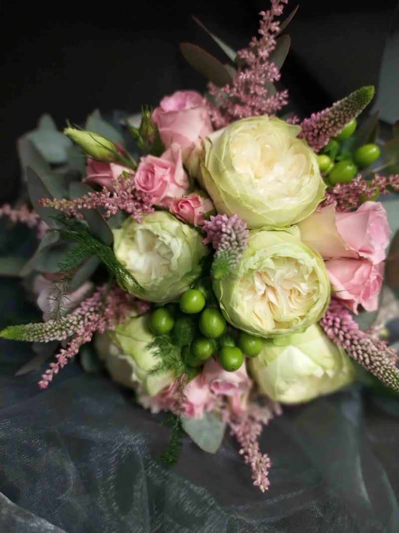 Bouquet de mariée de roses de jardin blanc-vert, de roses roses et d'astilbe, présenté sur un organza sombre