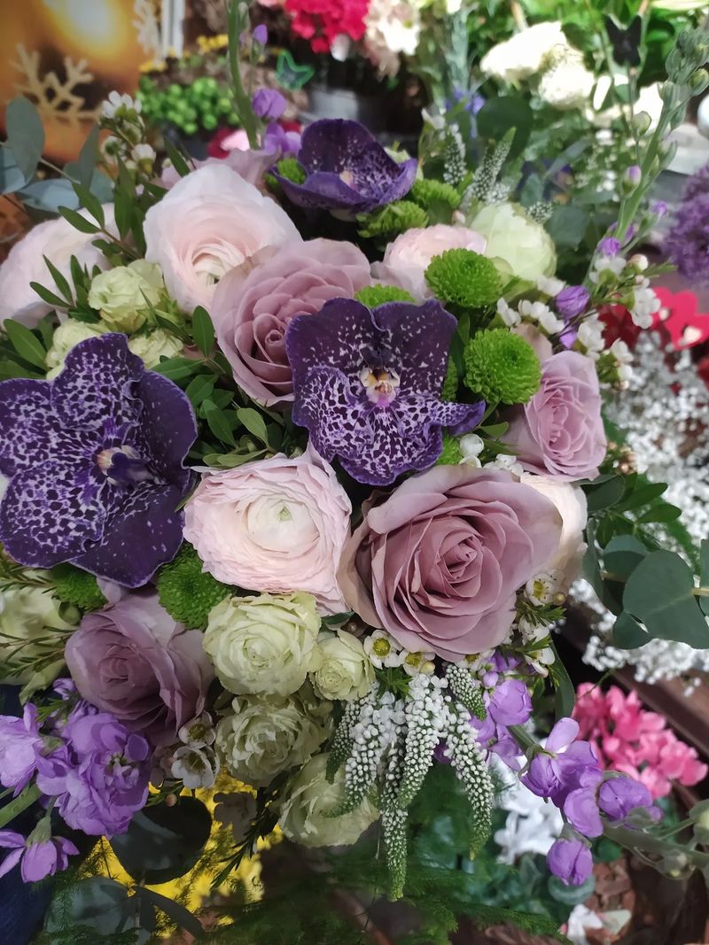 Gros plan sur les orchidées Vanda mouchetées, les roses mauves et les renoncules d'un bouquet
